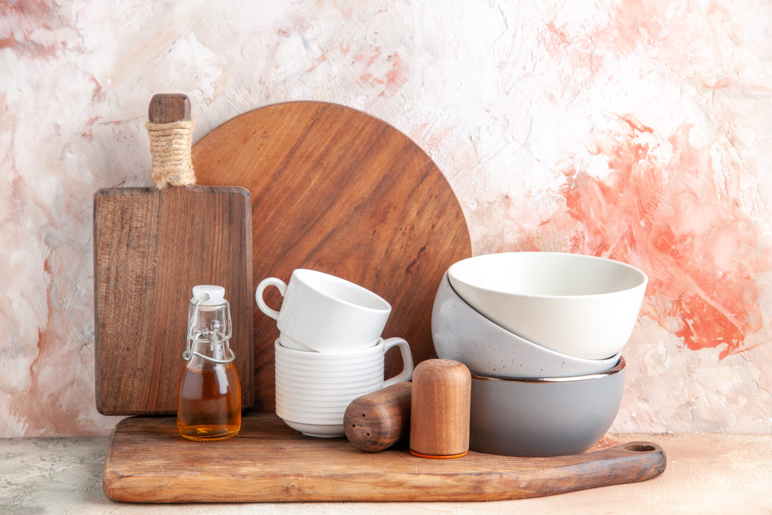 top-view-oil-bottle-stacked-pots-grater-wooden-cutting-board-colorful-surface (1)